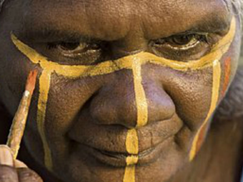 A traditional owner from the Tiwi Islands painting their face